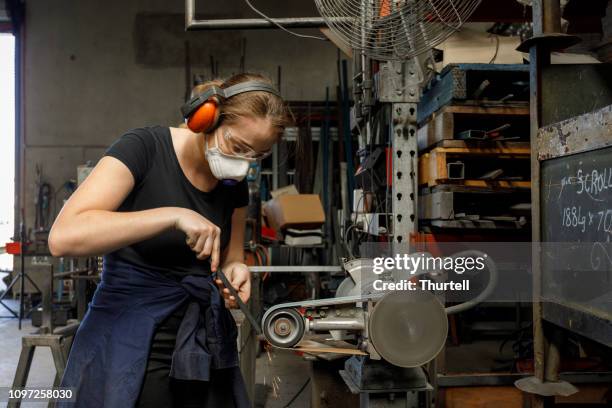 jonge australische vrouwelijke ook gordel sander met metaal workshop - metal sanding stockfoto's en -beelden