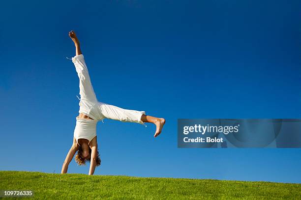 young woman doing cartwheel in a grassy field - cartwheel stock pictures, royalty-free photos & images