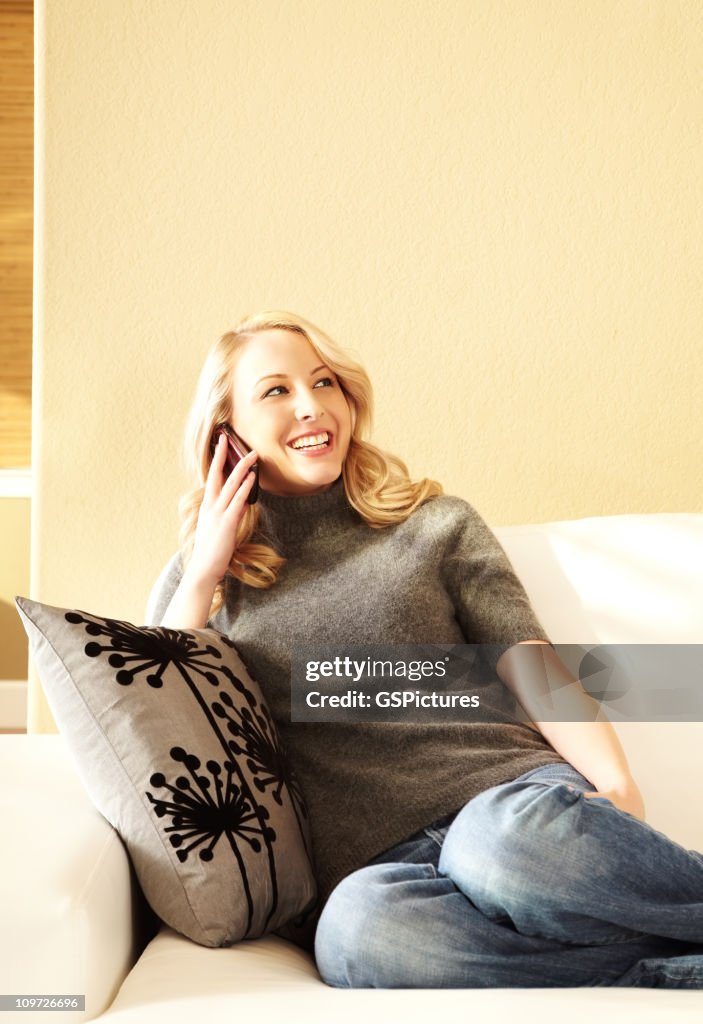 Young Woman Sitting on Couch and Using Cell Phone