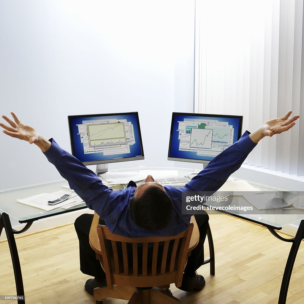 Businessman with Arms Raised at Desk