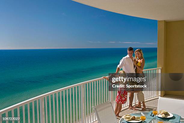 family of three on hotel balcony overlooking ocean - family holidays hotel stock pictures, royalty-free photos & images