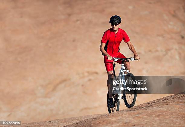 männliche athlet riding mountain bike bergauf auf slick rock trail - uphill stock-fotos und bilder