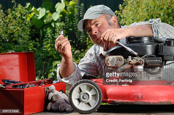 man working on a lawnmower in the garden. - grasmaaier stockfoto's en -beelden