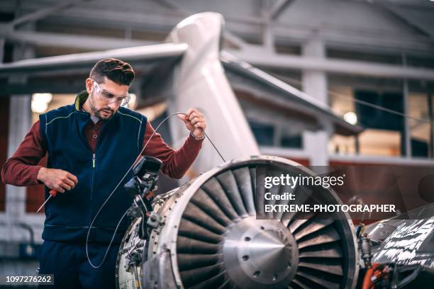 航空機整備士は携帯カメラで飛行機の開かれたジェット エンジンの調査と整備格納庫でモニターを見て - 機体尾部 ストックフォトと画像