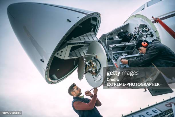 flugzeug-ingenieure arbeiten an einer radar-array unter der bugnase von einem privaten flugzeug geparkt auf einem flughafen-feld - aircraft maintenance stock-fotos und bilder