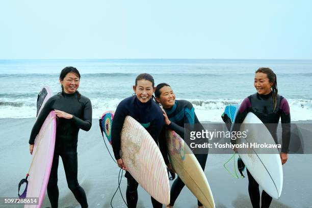 Surfer women are laughing in front of ocean