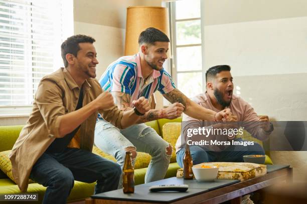 happy fans cheering while watching sports on tv - match 3 stock pictures, royalty-free photos & images