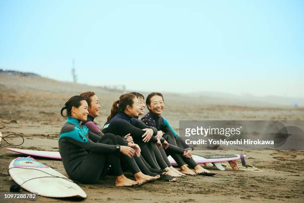 Surfer women are talking on beach in the rain