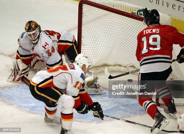 Jonathan Toews of the Chicago Blackhawks scores a goal in the 1st period against Miikka Kiprusoff of the Calgary Flames as Olli Jokinen tries to...