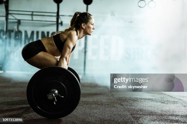 vista laterale della donna atletica che si allena deadlift in palestra. - sollevamento pesi foto e immagini stock