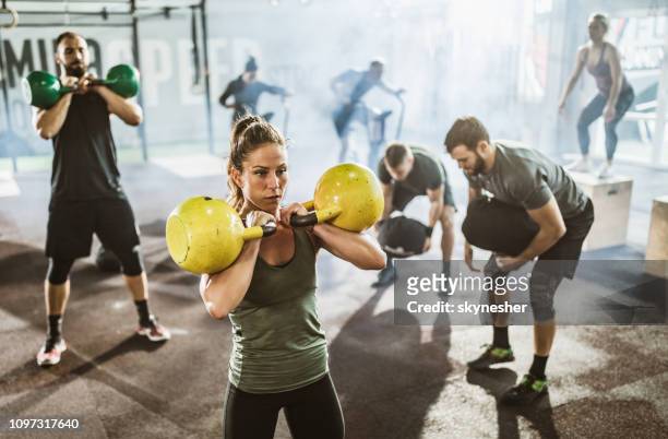 large group of athletes exercising strength of cross training in a gym. - circuit training stock pictures, royalty-free photos & images