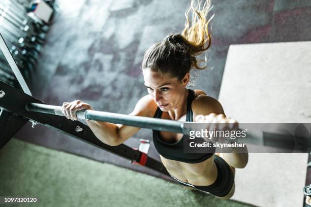 above view of athletic woman exercising chin-ups in a gym. - chin ups stock pictures, royalty-free photos & images