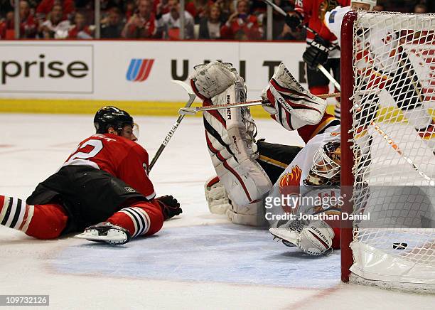 Troy Brouwer of the Chicago Blackhawks watches from the ice as the puck slips past Miikka Kiprusoff of the Calgary Flames on a goal by Jonathan Toews...