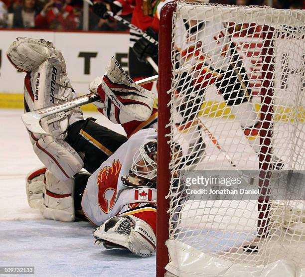 Miikka Kiprusoff of the Calgary Flames dives to try and stop the puck on a goal by Jonathan Toews of the Chicago Blackhawks at the United Center on...