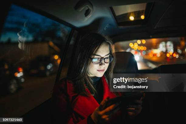 vacker ung kvinna med smart telefon i bilen - taxi bildbanksfoton och bilder