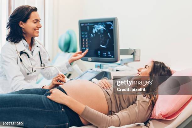 donna incinta che guarda il suo bambino sull'ecografia - obstetrician foto e immagini stock