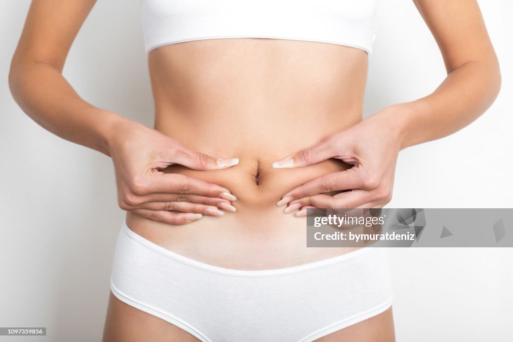 Woman pinching her stomach on white background