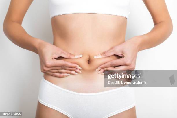 woman pinching her stomach on white background - women abdomen stock pictures, royalty-free photos & images