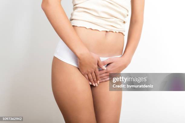 mujer con las manos sosteniendo su entrepierna - sistema urinario fotografías e imágenes de stock