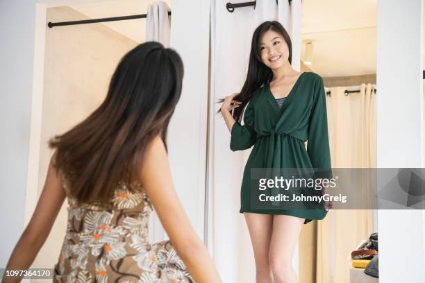 chinese woman trying on clothes with friend - mini dress stock pictures, royalty-free photos & images