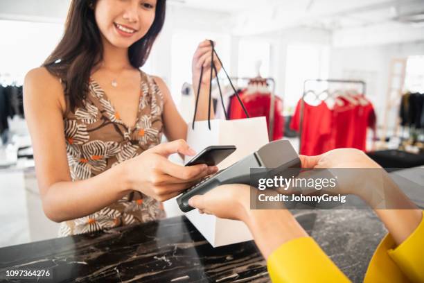 young woman paying contactlessly - asian credit card imagens e fotografias de stock