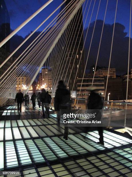 Pedestrians crossing Zubizuri or Calatrava's Footbridge at night, Bilbao, Spain, january 2010.