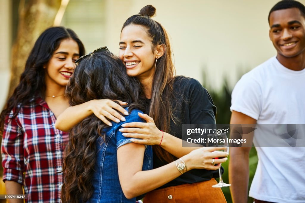 Smiling woman embracing friend at backyard party