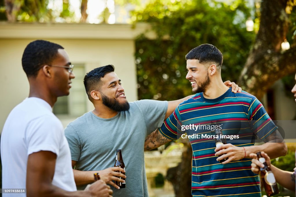 Happy male friends enjoying beer at backyard party