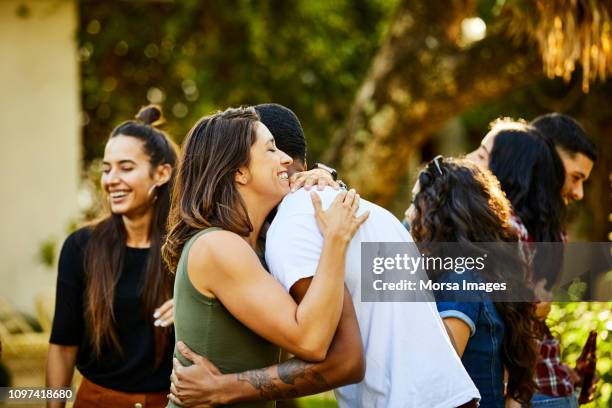 woman embracing friend in backyard during visit - solidarietà foto e immagini stock