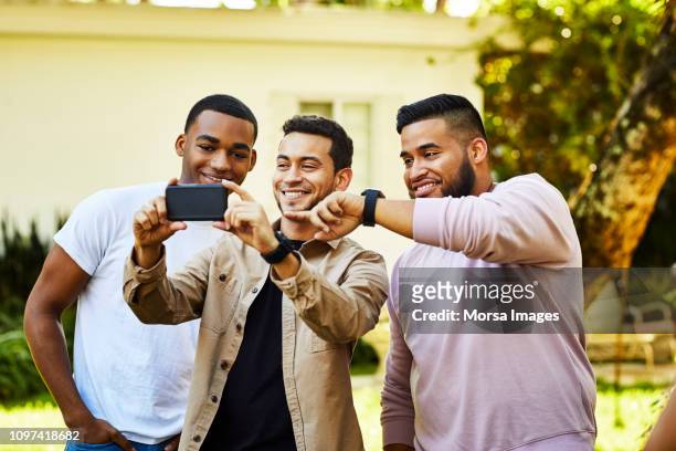 happy male friends taking selfie at garden party - nosotroscollection stockfoto's en -beelden