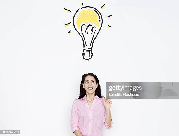 woman with drawing of lightbulb over her head - idea photos et images de collection