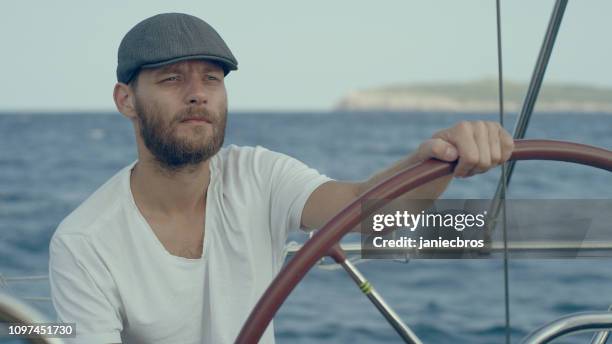 man steers the yacht - captains stock pictures, royalty-free photos & images