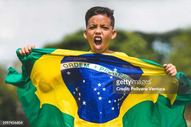 soccer player child holding brazilian flag - brazil flag stock pictures, royalty-free photos & images