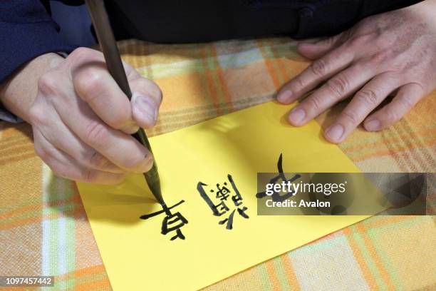 Taiwanese man writing Chinese calligraphy. Chinese calligraphy is a form of aesthetically pleasing writing. Chinese characters can be retraced to...