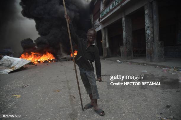 Boy stands before burning tires on the fourth day of protests in Port-au-Prince, on February 10, 2019. - Demonstrators are demanding the resignation...