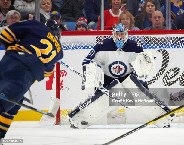 Kyle Okposo of the Buffalo Sabres takes a shot on Connor Hellebuyck of the Winnipeg Jets as he tends net during the third period at KeyBank Center on...