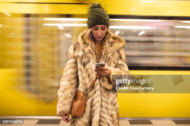 young woman at a train station texting on a mobile phone - berlin subway stock pictures, royalty-free photos & images