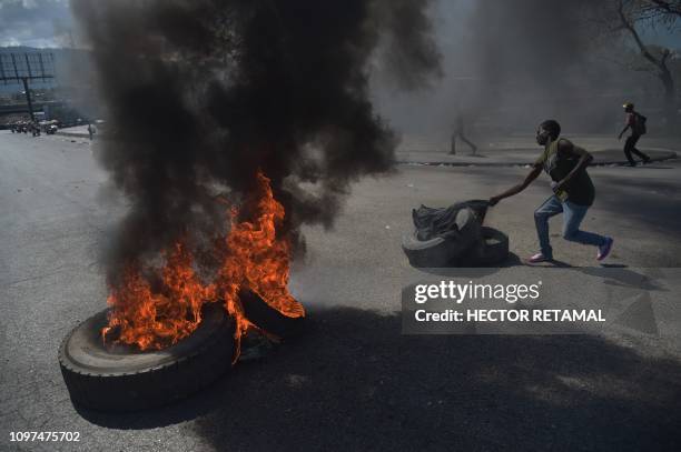 Demonstrator prepares to torch another tire on the fourth day of protests in Port-au-Prince, February 10 against Haitian President Jovenel Moise and...