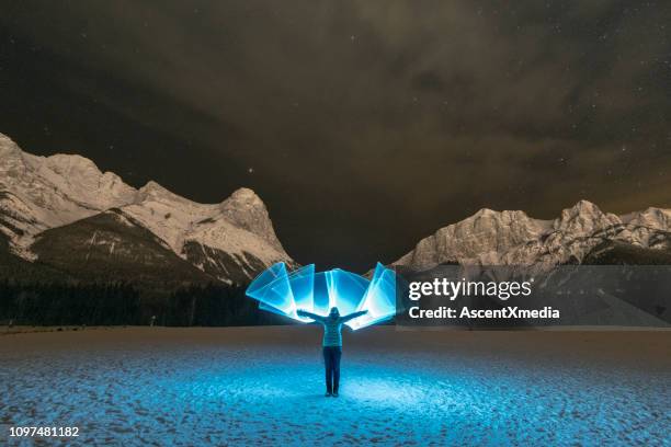 donna si trova in un campo innevato sotto le montagne in luce blu - canmore foto e immagini stock