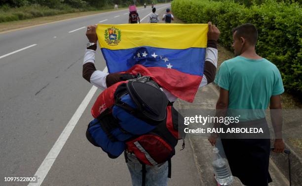 Venezuelan migrant holding a national flag walks with other migrants on the road from Cucuta to Pamplona, in Norte de Santander Department, Colombia,...