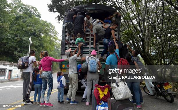 Venezuelan migrants climb on a truck on the road from Cucuta to Pamplona, in Norte de Santander Department, Colombia, on February 10, 2019. -...