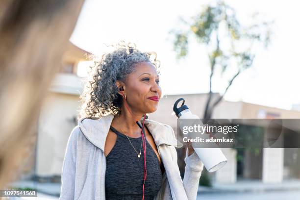 mujer negra tomando una bebida del agua mientras que trabaja hacia fuera - skinny black woman fotografías e imágenes de stock