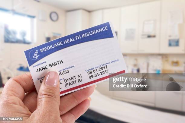woman holding medicare card in medical office - medicare stock pictures, royalty-free photos & images