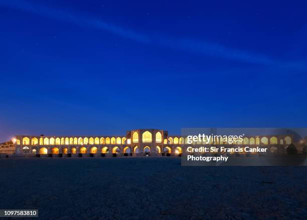 khaju bridge ("pol-e khaju") illuminated at late dusk over zayandeh river in isfahan, iran - isfahan stock pictures, royalty-free photos & images