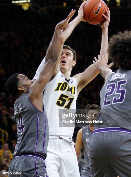 Forward Nicholas Baer of the Iowa Hawkeyes goes to the basket in the second half between forward Vic Law and center Barret Bensin of the Northwestern...