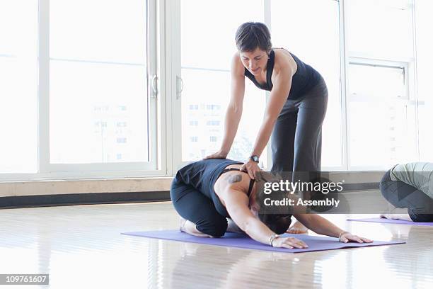 yoga instructor helping students with poses - yoga instructor stock pictures, royalty-free photos & images