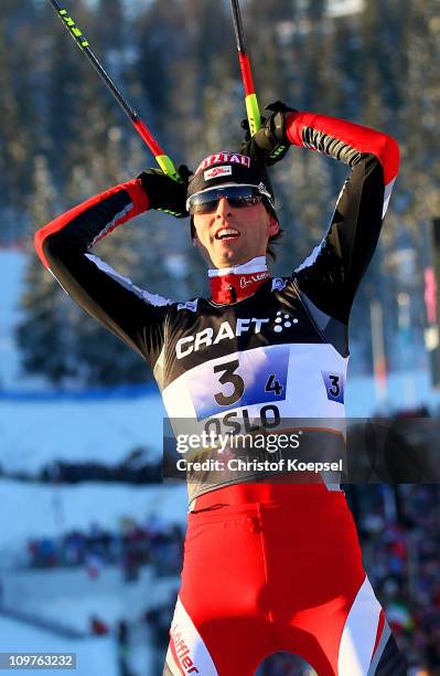 Mario Stecher of Austria celebrates winning the gold medal as he crosses the finish line in the Nordic Combined Team 4x5km race during the FIS Nordic...