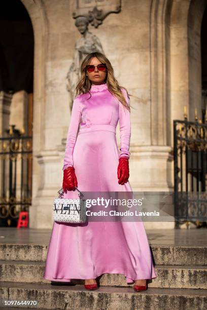 Erica Pelosini Leeman, wearing a long pink dress, red Gucci gloves, red heels and Valentino white bag, is seen outside Schiaparelli during Paris...