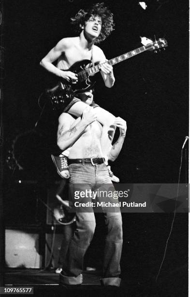 Guitarist Angus Young of Australian rock band AC/DC being carried on the shouilders of singer Bon Scott while performing on stage at the Town Hall in...