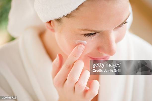 woman applying lotion to face - self improvement stock pictures, royalty-free photos & images